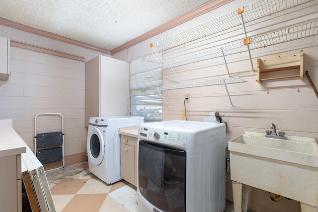 clothes washing area with cabinets, sink, independent washer and dryer, a textured ceiling, and ornamental molding