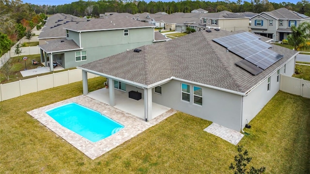 back of house featuring a yard, a fenced in pool, solar panels, and a patio