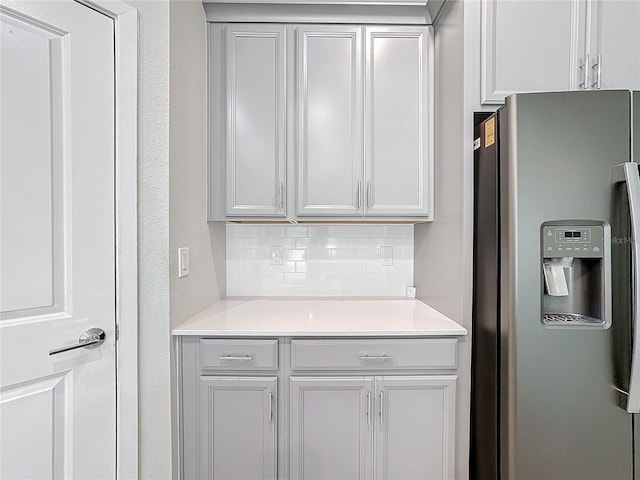 kitchen with decorative backsplash, stainless steel fridge with ice dispenser, and white cabinetry