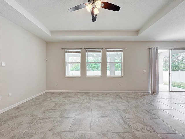 spare room featuring ceiling fan, a textured ceiling, a raised ceiling, and light tile patterned flooring