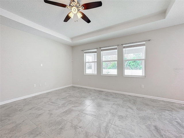 unfurnished room with ceiling fan, a textured ceiling, and a raised ceiling