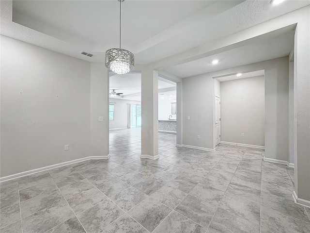 empty room featuring ceiling fan with notable chandelier