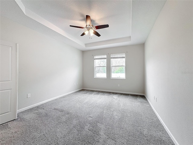 spare room featuring a textured ceiling, ceiling fan, carpet flooring, and a raised ceiling