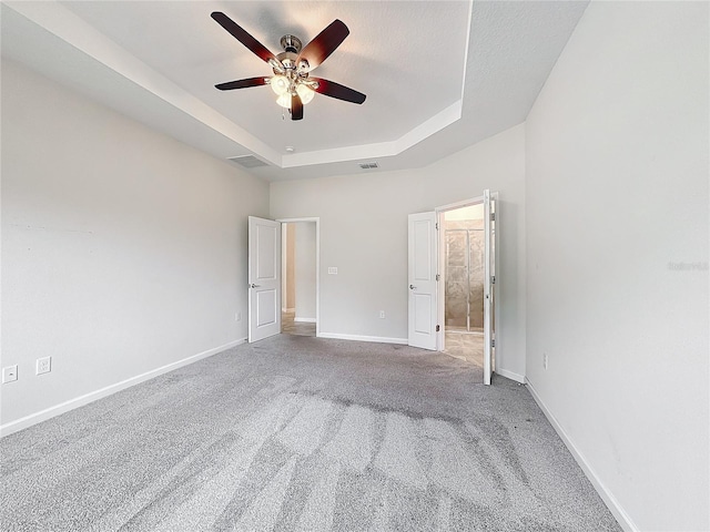 unfurnished bedroom featuring ceiling fan, carpet flooring, and a raised ceiling