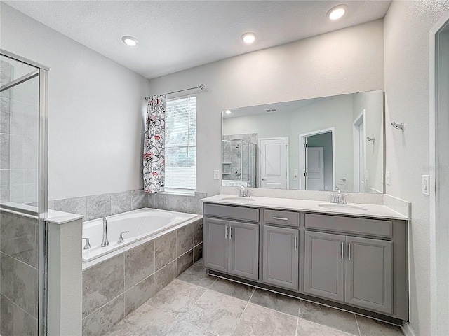 bathroom featuring a textured ceiling, vanity, and shower with separate bathtub