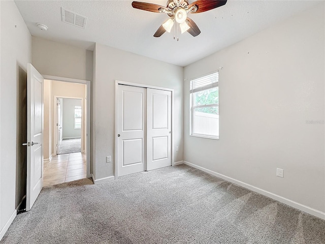 unfurnished bedroom with ceiling fan, a closet, and light colored carpet