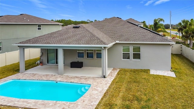 rear view of property featuring a fenced in pool, a yard, and a patio