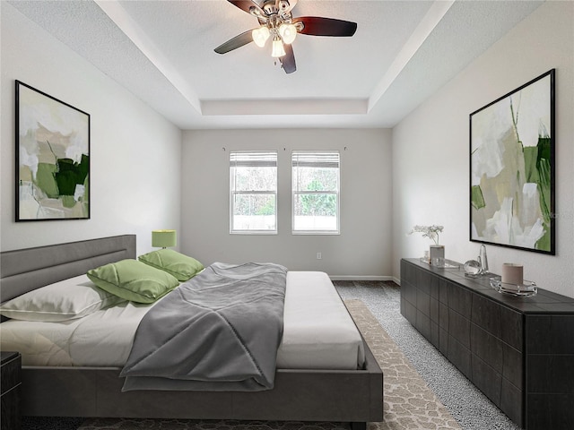 carpeted bedroom featuring ceiling fan and a tray ceiling