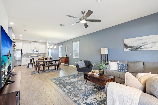 living room with light hardwood / wood-style flooring and ceiling fan with notable chandelier