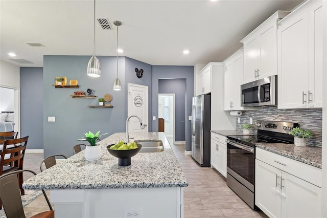 kitchen featuring stainless steel appliances, a center island with sink, and sink