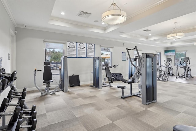 gym with a raised ceiling, ornamental molding, and light carpet