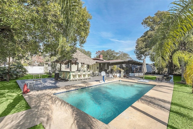 view of swimming pool with exterior bar, a patio area, and a yard