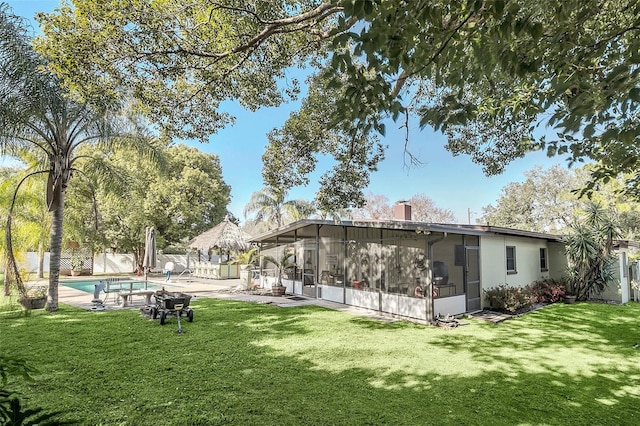 rear view of property featuring a fenced in pool, a sunroom, and a lawn