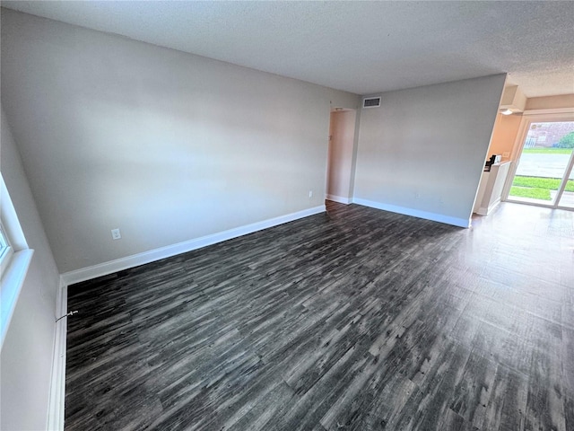 unfurnished room with a textured ceiling and dark hardwood / wood-style floors