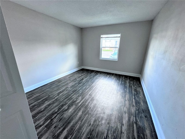 unfurnished room with a textured ceiling and dark wood-type flooring