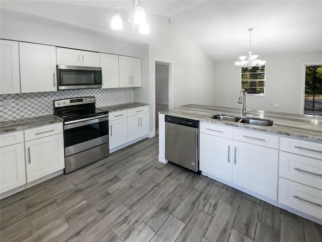 kitchen featuring decorative light fixtures, sink, stainless steel appliances, and vaulted ceiling