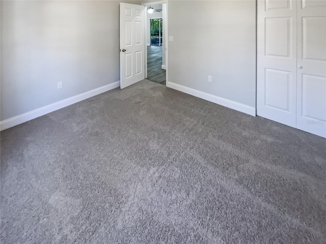 unfurnished bedroom with dark carpet and a closet