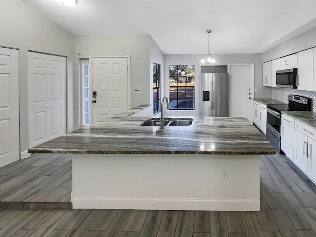 kitchen with appliances with stainless steel finishes, a kitchen island, sink, white cabinetry, and hanging light fixtures