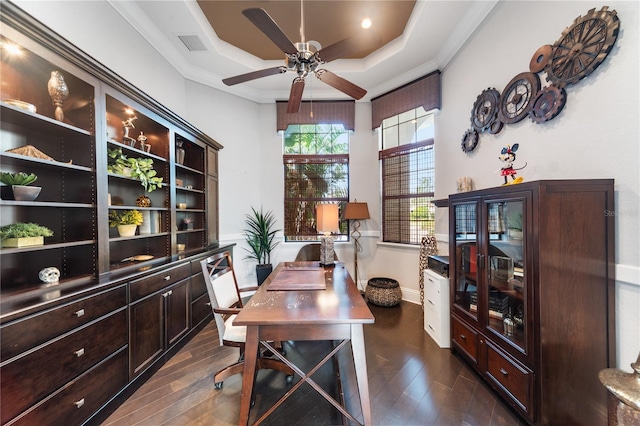 home office featuring dark hardwood / wood-style flooring, a tray ceiling, ceiling fan, and crown molding