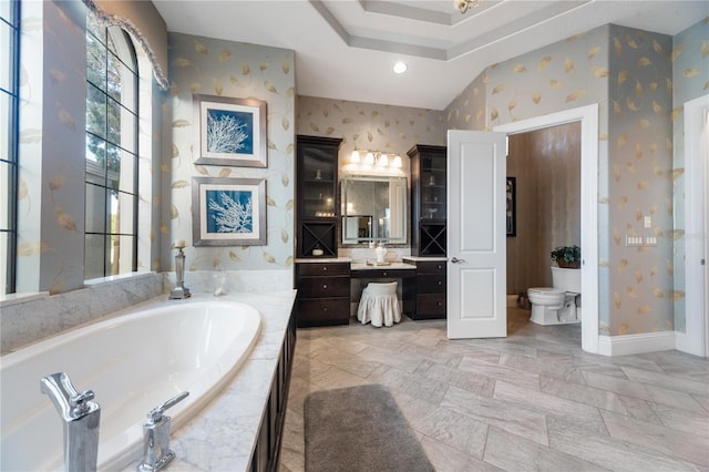 bathroom with vanity, toilet, and tiled tub