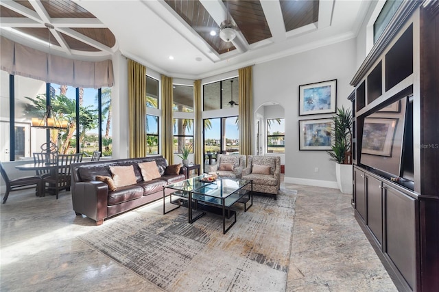 living room featuring a high ceiling, coffered ceiling, crown molding, ceiling fan, and beamed ceiling