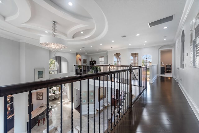 hallway featuring wood-type flooring, ornamental molding, and a notable chandelier