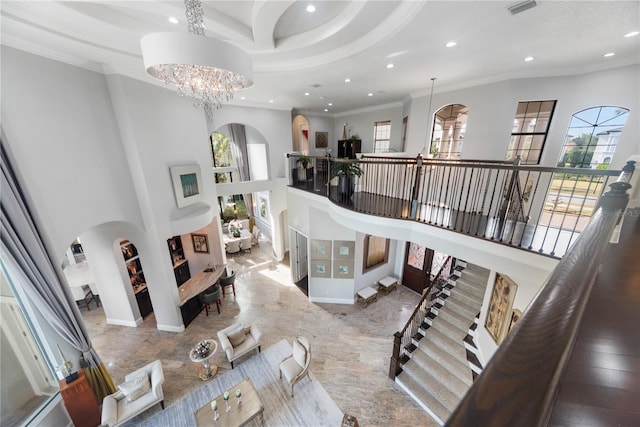 staircase featuring a towering ceiling, ornamental molding, and a chandelier