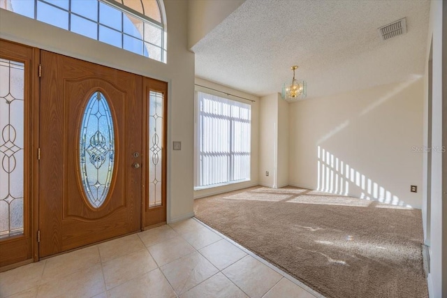 entrance foyer with light tile patterned floors, a textured ceiling, and an inviting chandelier