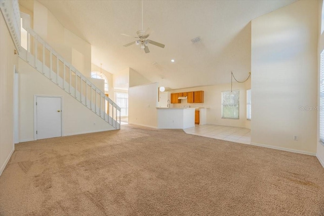 unfurnished living room with light carpet, high vaulted ceiling, a healthy amount of sunlight, and ceiling fan