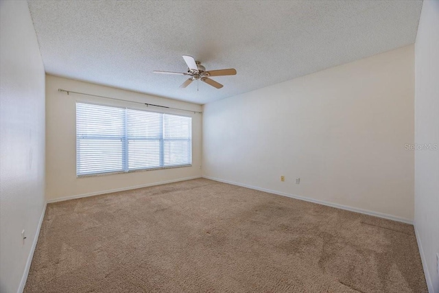 spare room with a textured ceiling, light colored carpet, and ceiling fan