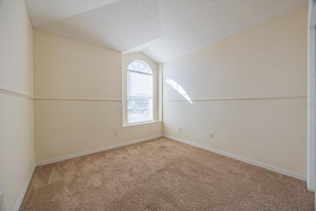 empty room featuring light colored carpet, lofted ceiling, and a textured ceiling