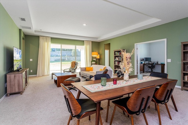 carpeted dining room with a raised ceiling