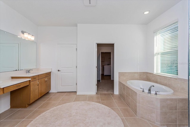 bathroom with tile patterned flooring, vanity, washer / dryer, and tiled bath