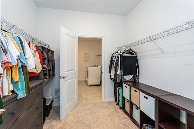 walk in closet with washer / dryer and light colored carpet