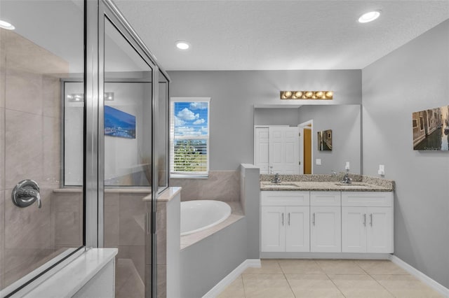 bathroom with tile patterned flooring, vanity, a textured ceiling, and separate shower and tub