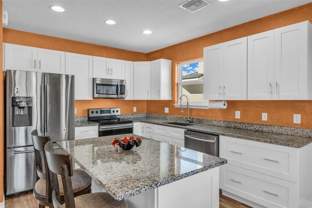 kitchen featuring white cabinetry, a center island, sink, and appliances with stainless steel finishes