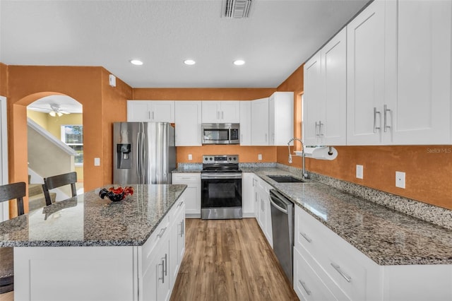 kitchen featuring stainless steel appliances, ceiling fan, sink, white cabinetry, and a kitchen island