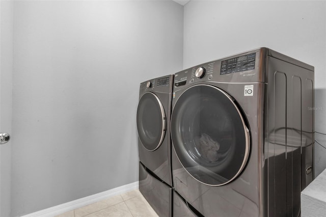 laundry room featuring washing machine and dryer and light tile patterned floors