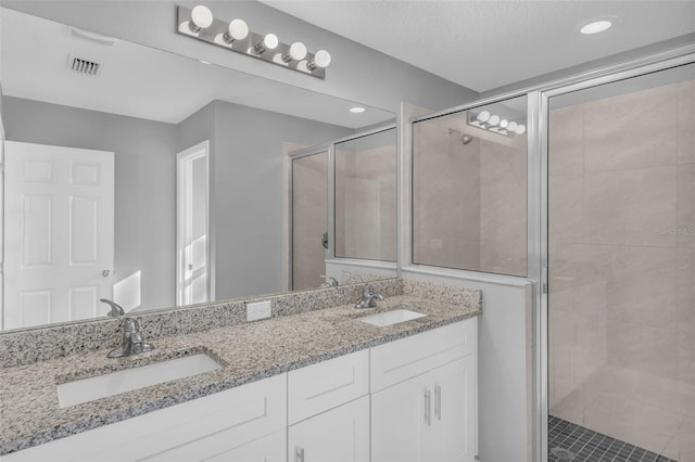 bathroom with vanity, an enclosed shower, and a textured ceiling