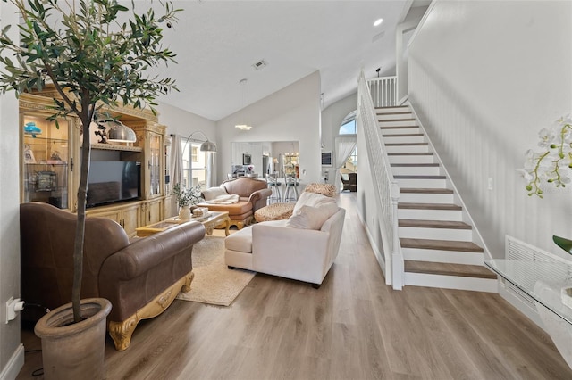 living room featuring high vaulted ceiling and light wood-type flooring