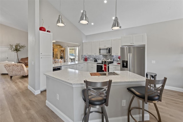 kitchen featuring a breakfast bar, sink, appliances with stainless steel finishes, high vaulted ceiling, and white cabinets