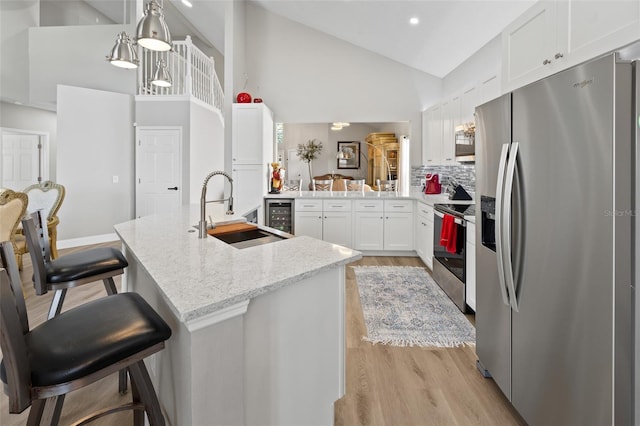 kitchen with tasteful backsplash, kitchen peninsula, sink, a kitchen breakfast bar, and stainless steel appliances