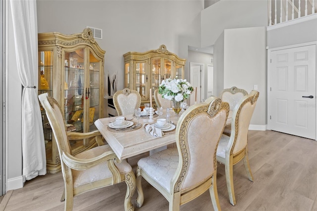 dining space featuring light hardwood / wood-style flooring and a towering ceiling