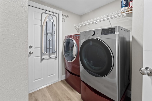 laundry area with washing machine and dryer and light hardwood / wood-style floors