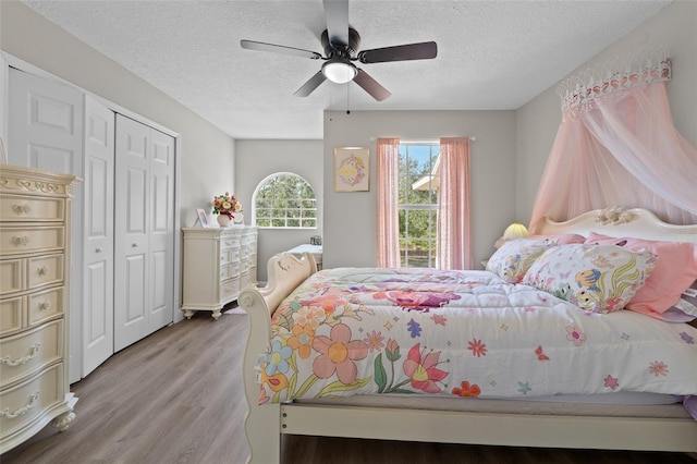 bedroom with ceiling fan, a closet, a textured ceiling, and light hardwood / wood-style flooring