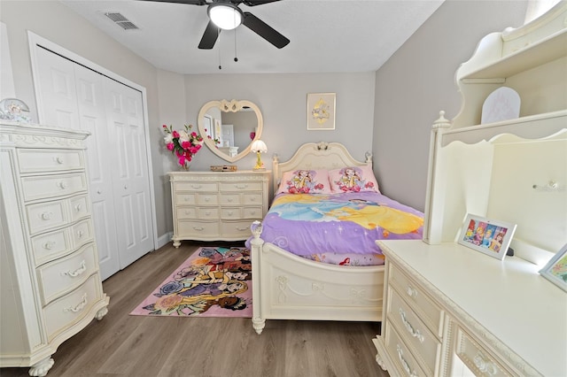 bedroom with ceiling fan, dark wood-type flooring, and a closet