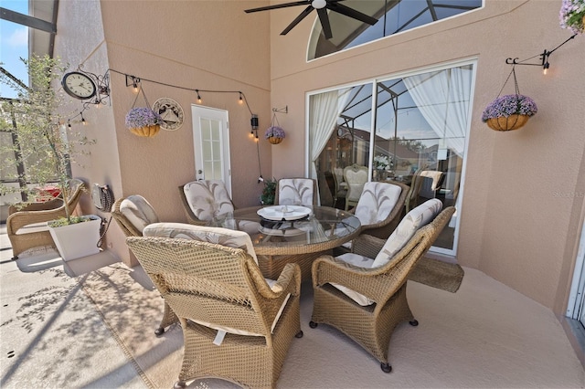 view of patio with ceiling fan and glass enclosure