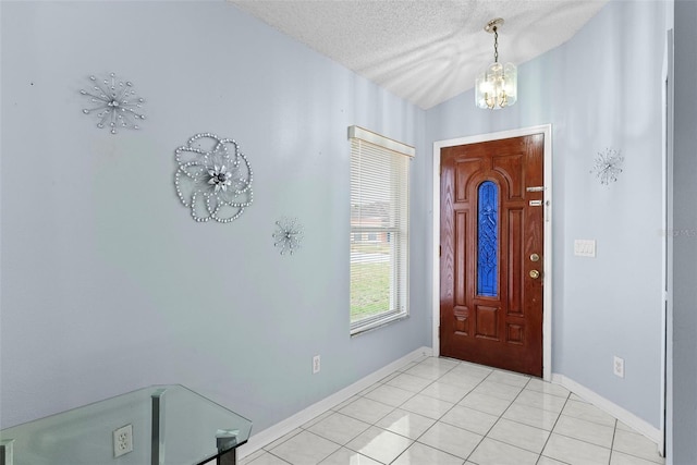 tiled foyer with a textured ceiling, a chandelier, and vaulted ceiling