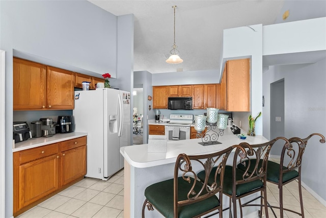 kitchen with pendant lighting, white appliances, light tile patterned floors, and kitchen peninsula