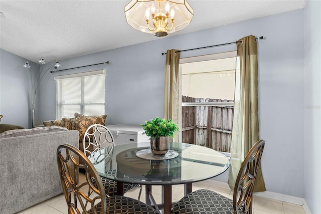 tiled dining area with a chandelier and a textured ceiling